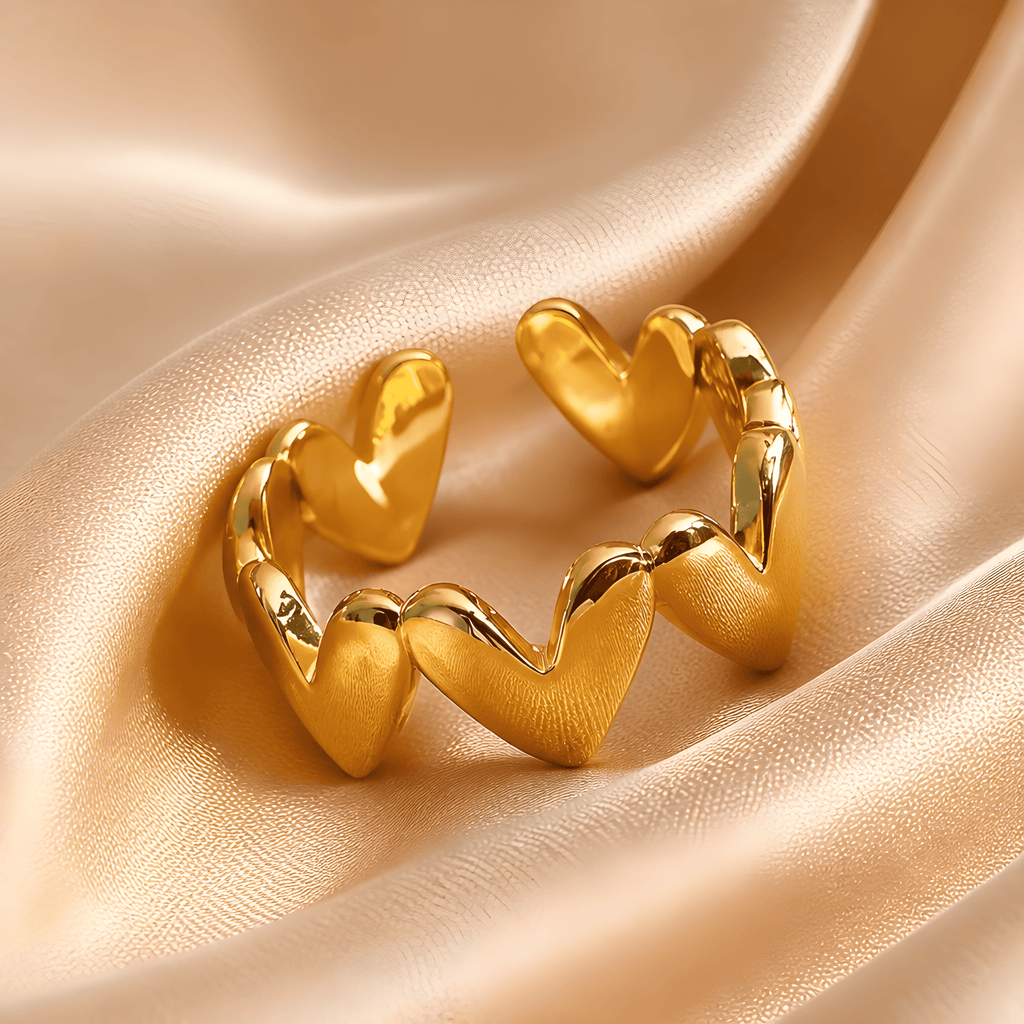 Goldfarbener Herzring mit glänzenden Herzen auf champagnerfarbenem Satin