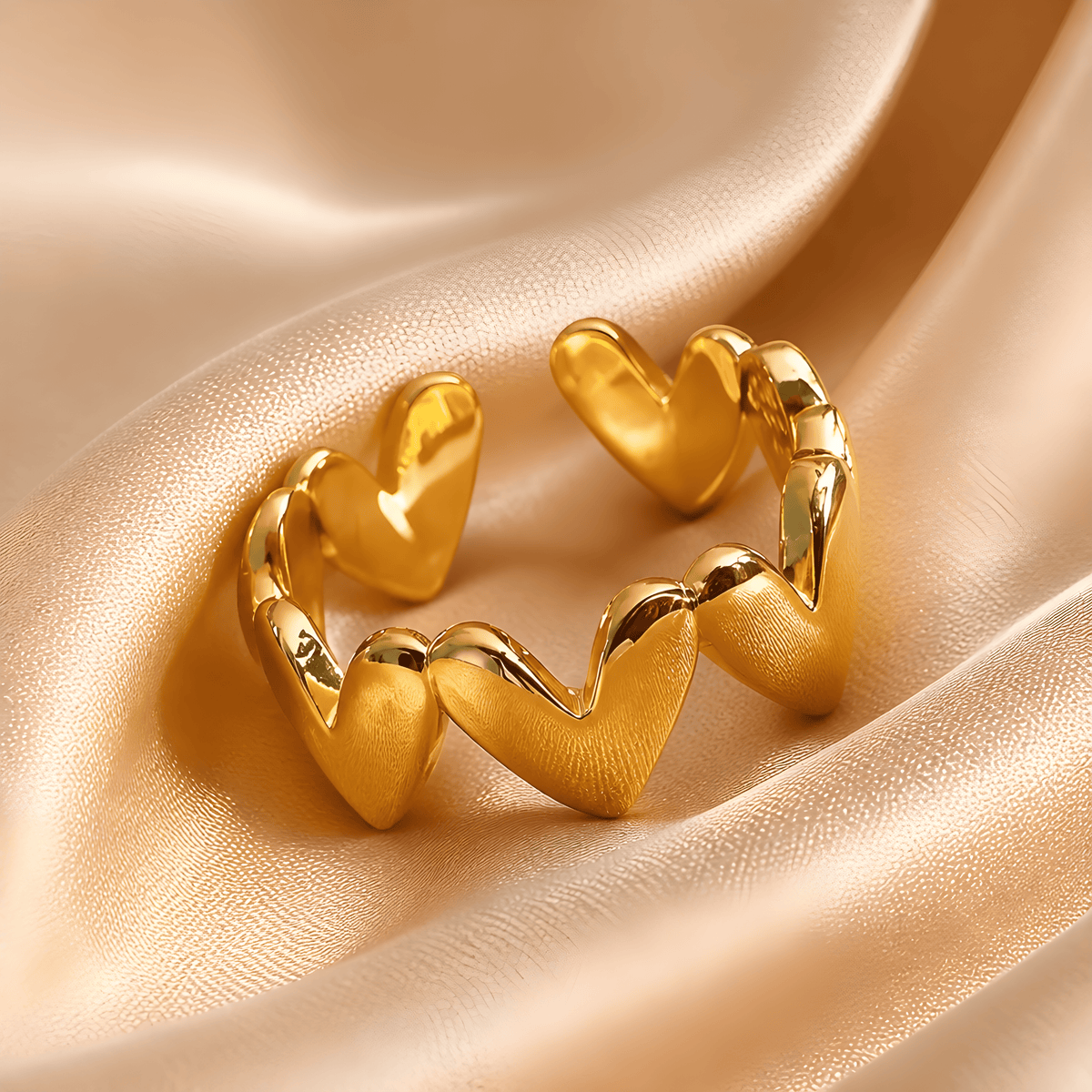 Goldfarbener Herzring mit glänzenden Herzen auf champagnerfarbenem Satin