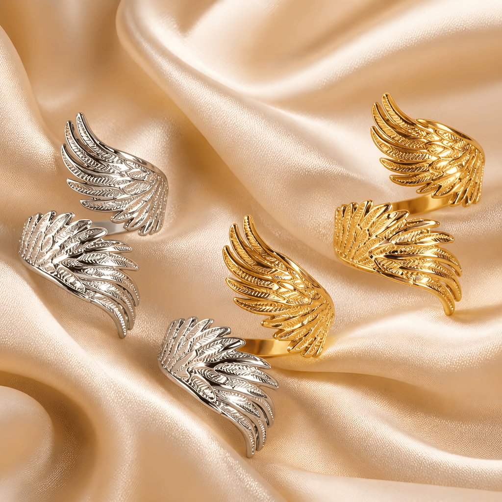 Goldfarbene und silberfarbene Flügelringe auf champagnerfarbenem Satin