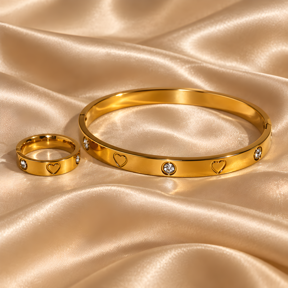Goldfarbenes Juliette Armband und Herzring mit Zirkonia auf champagnerfarbenem Satin