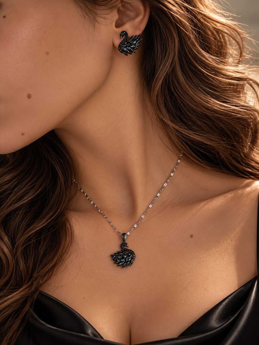 Model trägt das Onyx Schwan-Set: silberfarbene Kette mit schwarzem Schwan-Anhänger und passendem schwarzem Schwan-Ohrstecker zu schwarzem Oberteil