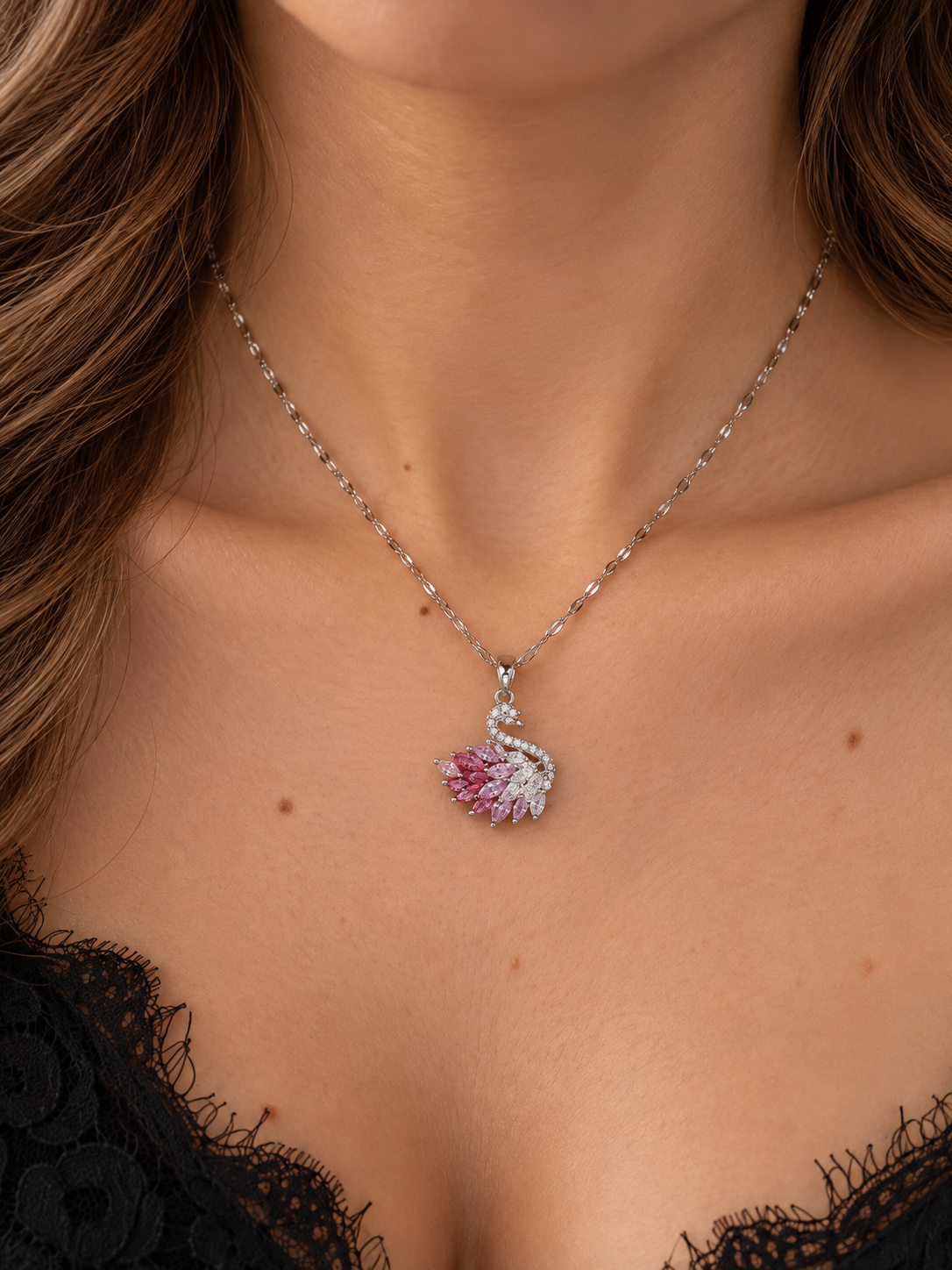 Model trägt das Rosentraum Schwan-Collier: silberfarbene Kette mit rosa-weißem Schwan-Anhänger zu schwarzem Oberteil