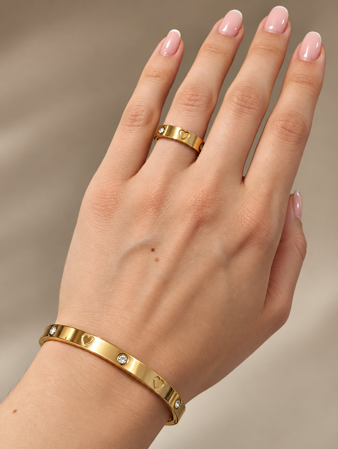 Goldfarbener Juliette Ring und passender Armreif mit Herzen und Zirkonia an der Hand getragen