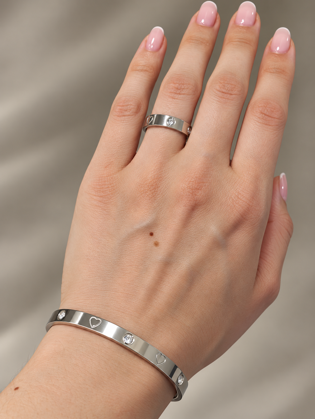 Silberfarbener Juliette Ring und passender Armreif mit Herzen und Zirkonia an der Hand getragen
