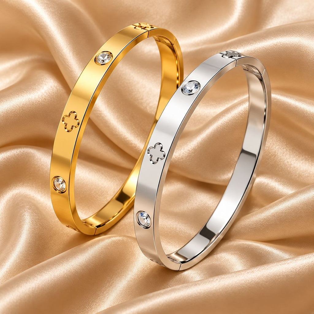 Goldfarbener und silberfarbener Chloé Armreif mit Kleeblatt-Motiven und klaren Steinen auf champagnerfarbenem Satin