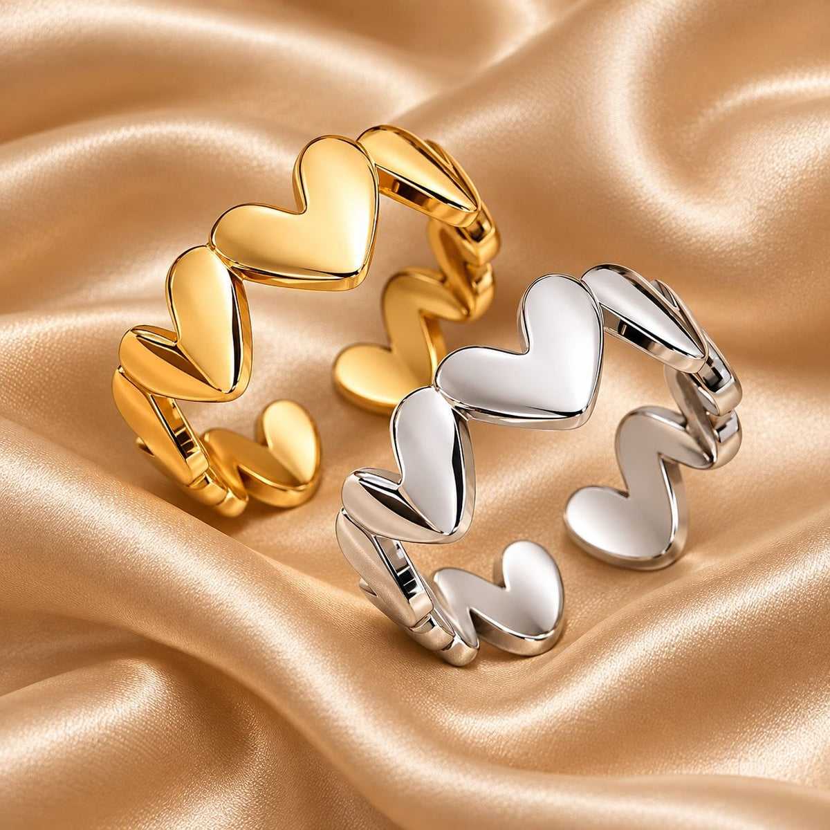 Goldfarbener und silberfarbener Herzband Ring auf champagnerfarbenem Satin